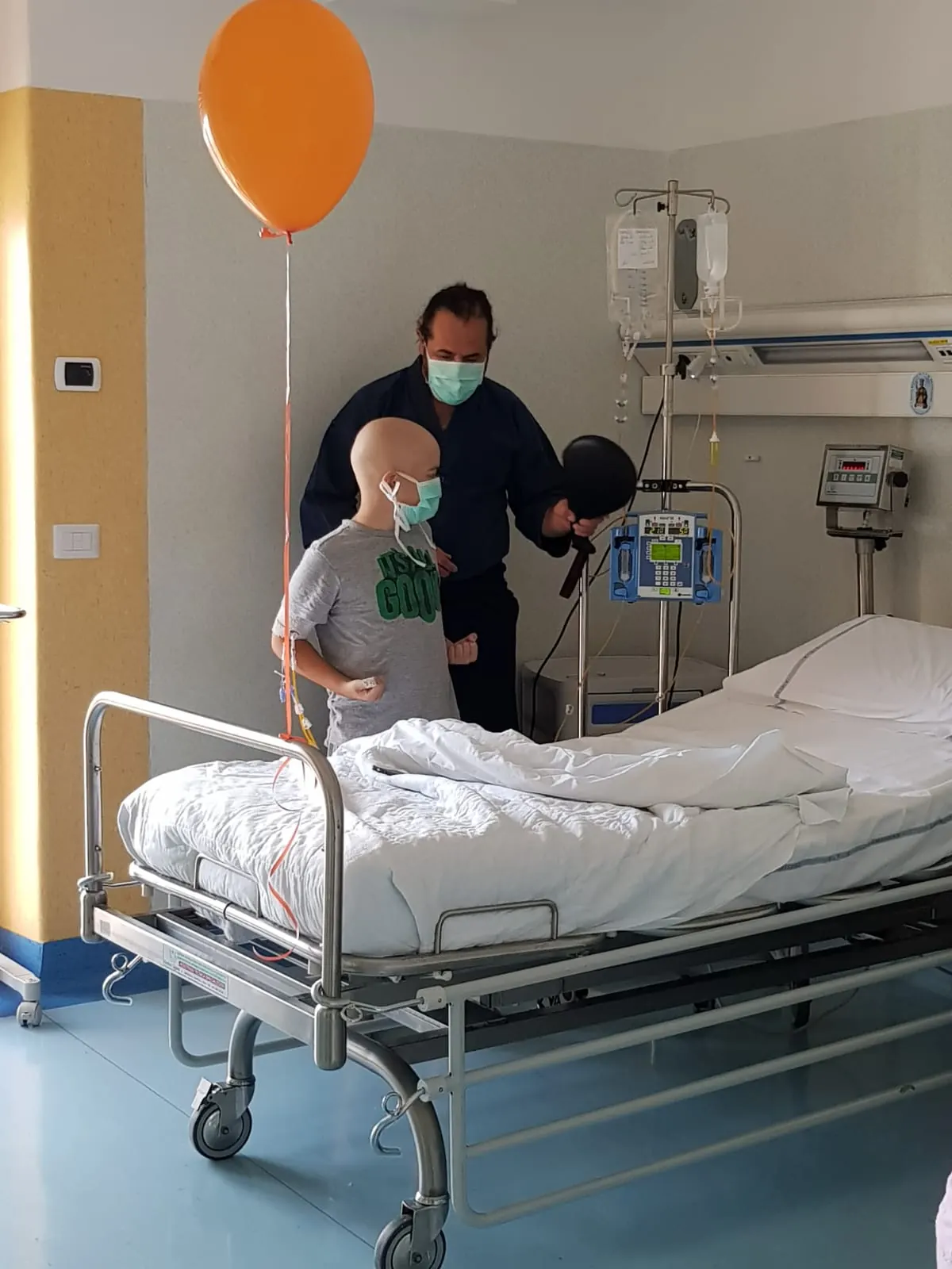 Un copil cu masca sta langa patul de spital in timp ce instructorii pregatesc exercitiul.